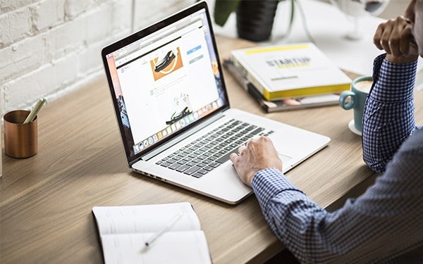 Building a freelance copywriting business - copywriter sat at work desk working from a laptop with a notebook and pen to the left of the laptop
