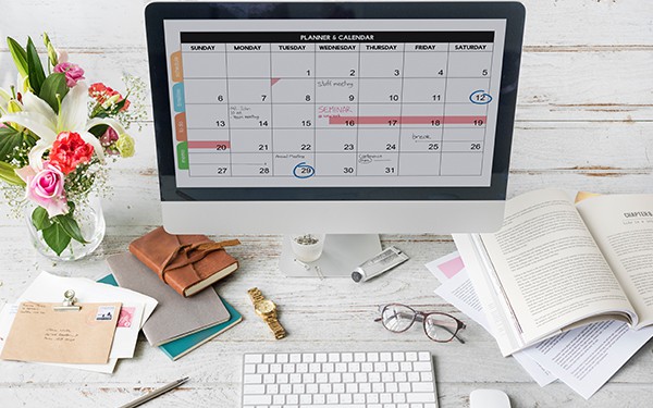 Work calendar on iMac computer placed on white work desk