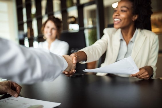 What is the recruitment process - A woman shaking the hand of a potential employee during an interview
